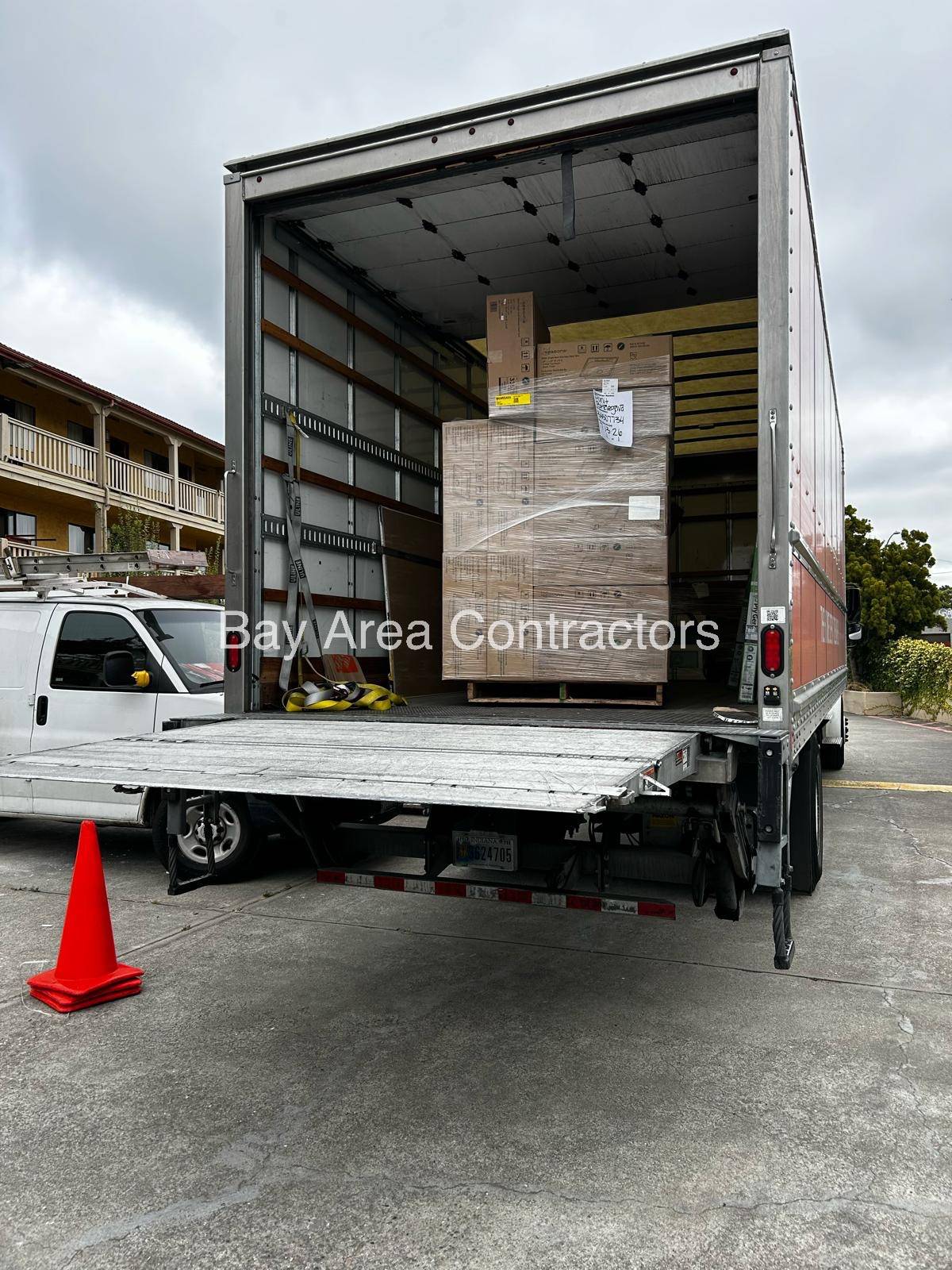 Box truck with its liftgate down delivering palletized materials to a job site