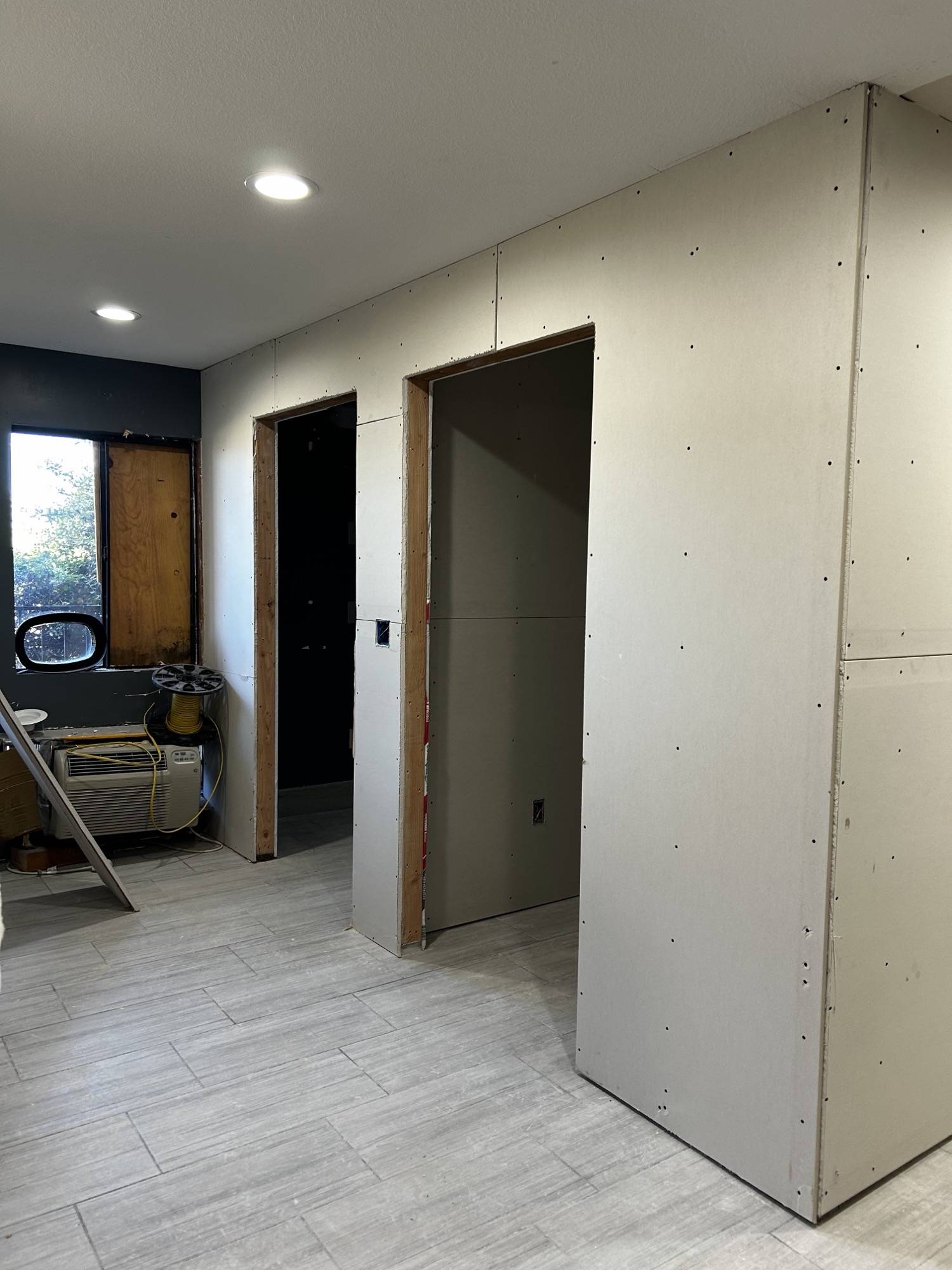 New drywall hung in a commercial interior with recessed lighting and tile flooring