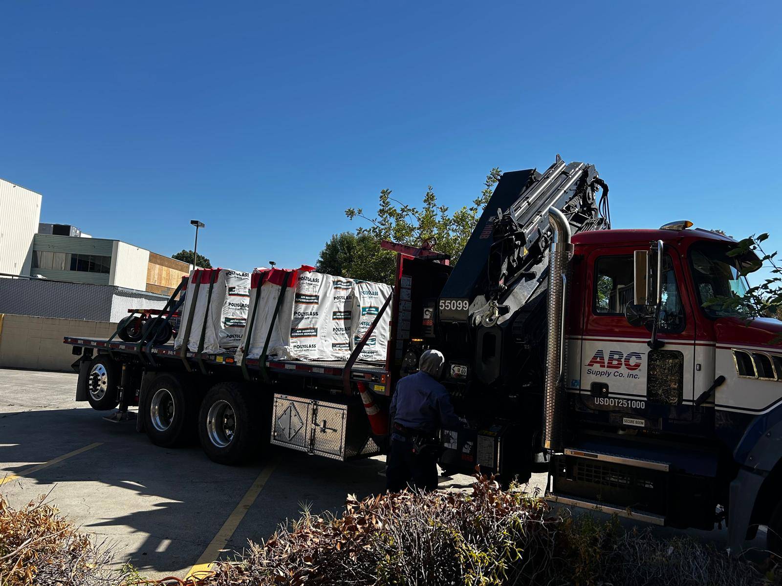 Crane truck delivering palletized roofing membrane to a job site