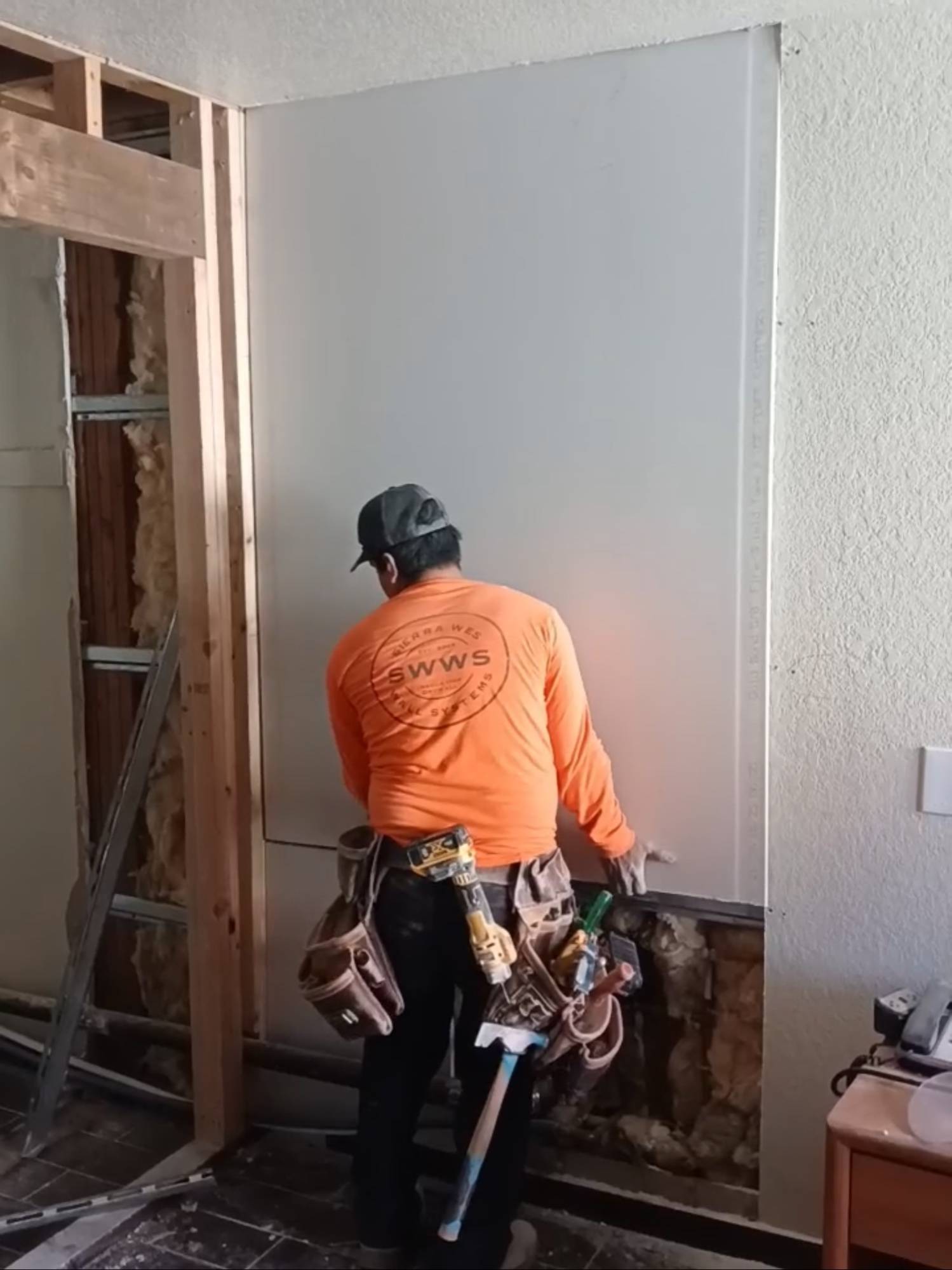 Drywaller fitting a sheet over new framing during an interior build-out