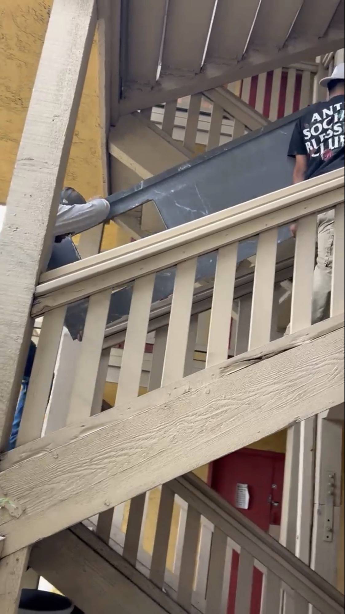 Crew carrying a stone countertop up an exterior staircase to an upper unit
